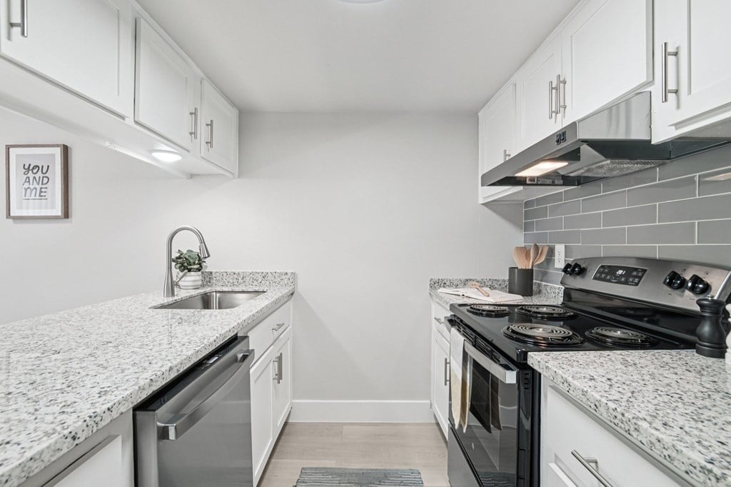One Bedroom Apartments in North Mountain Village, Phoenix, AZ - Ardella on 28th - Kitchen with Wood-Style Flooring, Granite Countertops, Stainless Steel Appliances, and White Cabinetry.