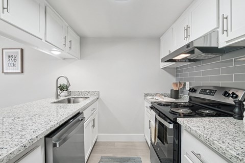 A kitchen with a granite countertop and a stove top oven.