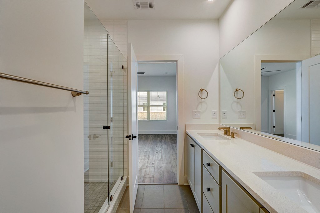 Bathroom with shower, sink, and large mirror at Henley Avondale in Avondale Estates, GA, in a pet-friendly community.