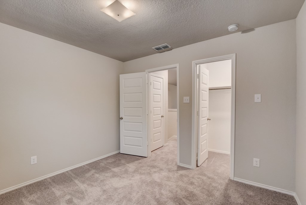 an empty bedroom with a closet and an open door