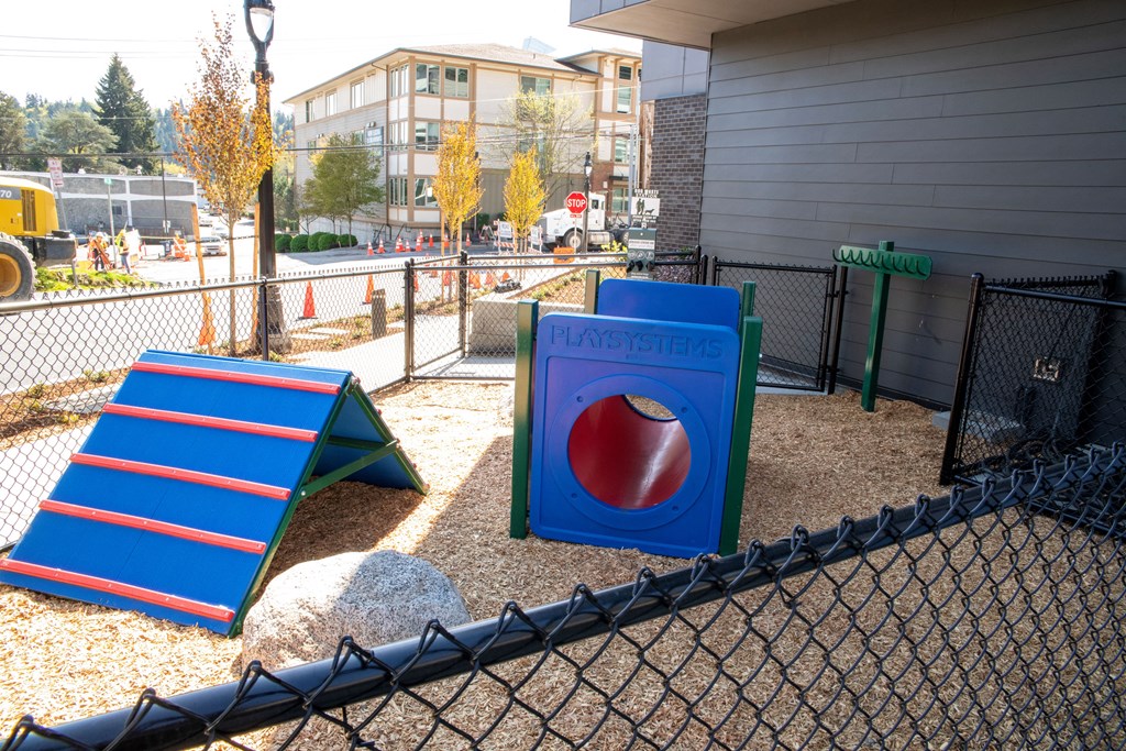a playground with a seesaw and slides in a fenced in area