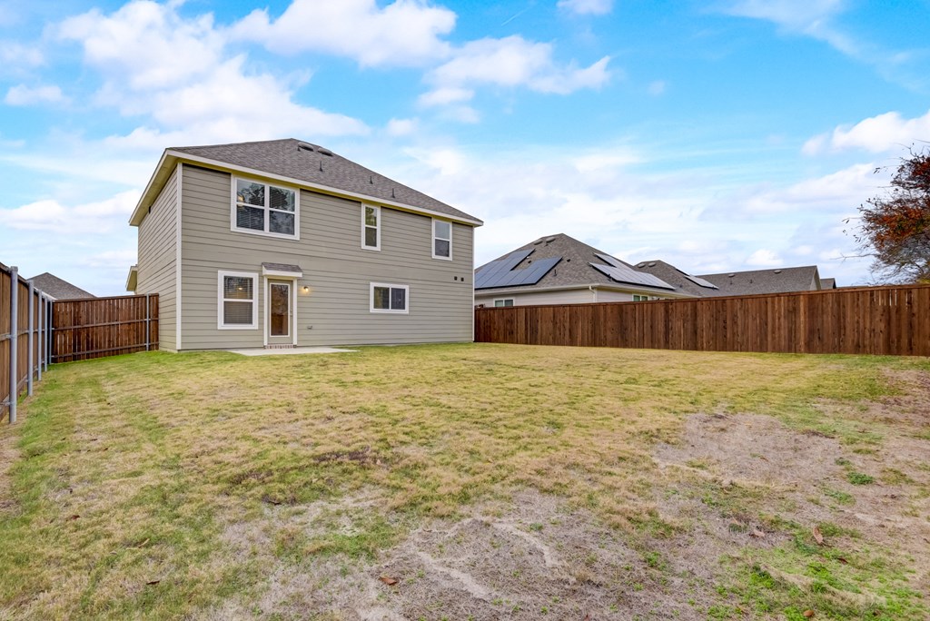 a backyard with a house and a wooden fence