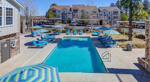 A large swimming pool surrounded by blue lounge chairs and umbrellas.