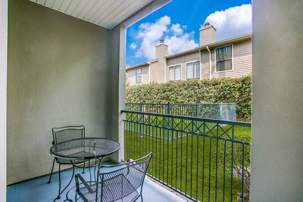 a balcony with a table and chairs and a fence