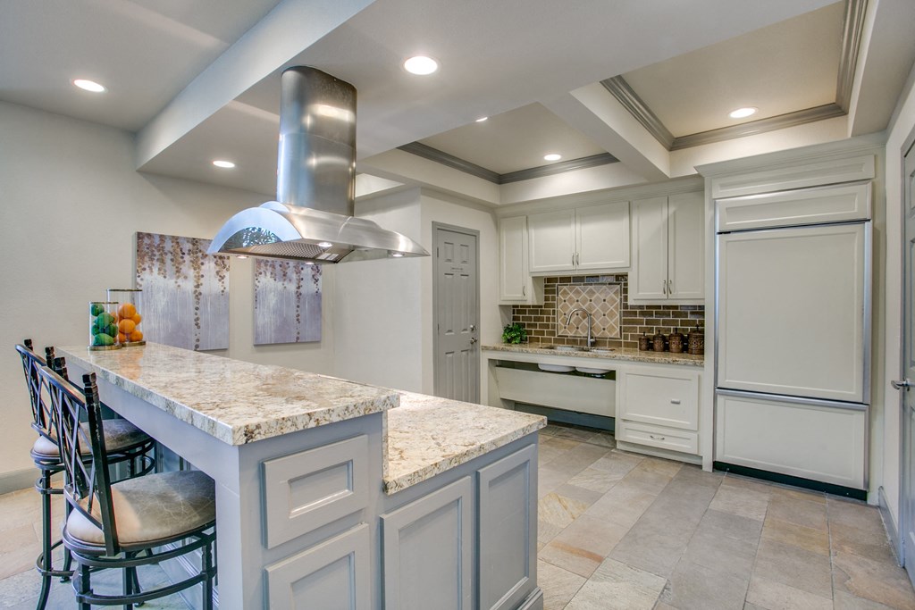 a kitchen with white cabinets and a marble counter top