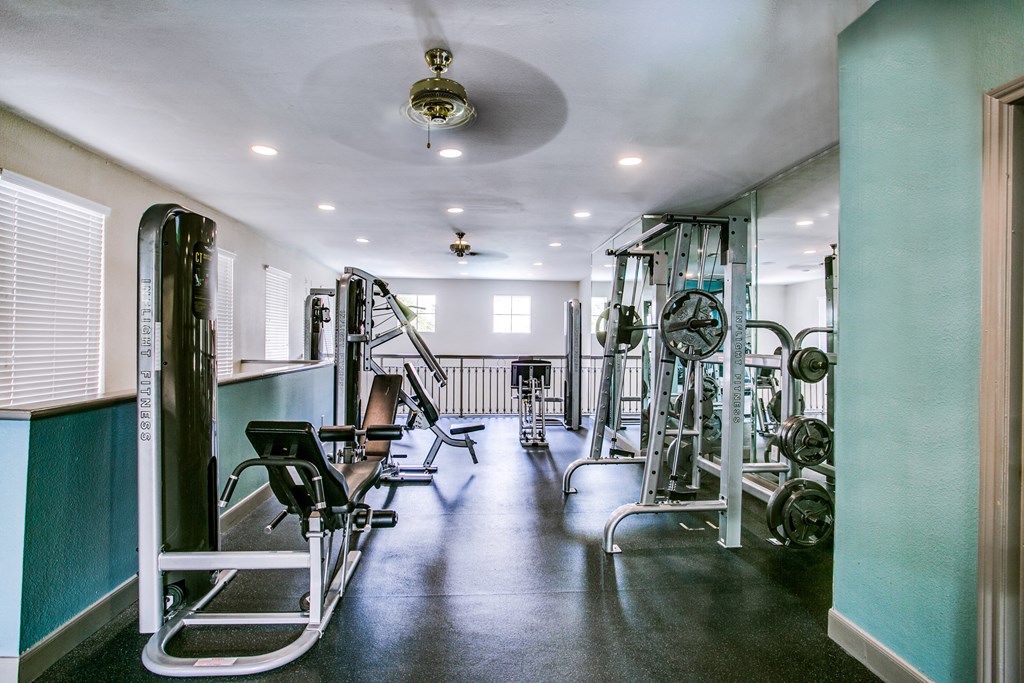 a fitness room with weights and a ceiling fan