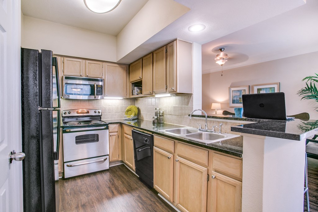 a kitchen with wooden cabinets and black counter tops and white appliances