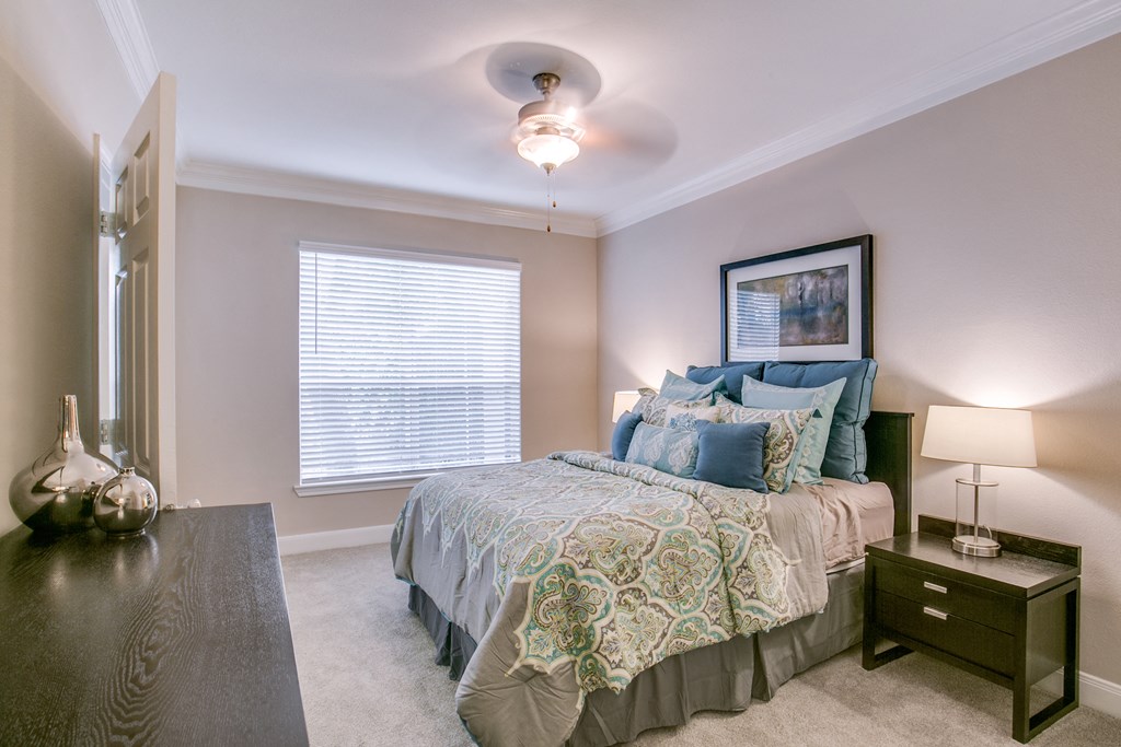 a bedroom with a bed and a dresser and a ceiling fan