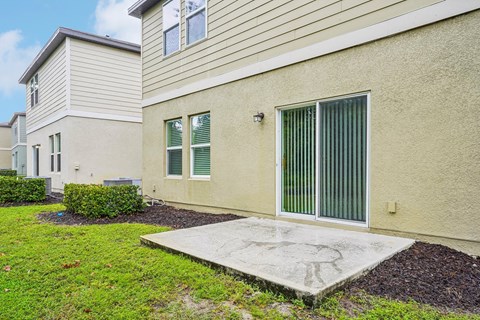 A beige house with a green window and a grey door.