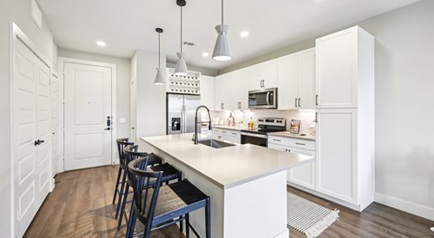 A kitchen with white cabinets and a white island with a sink.