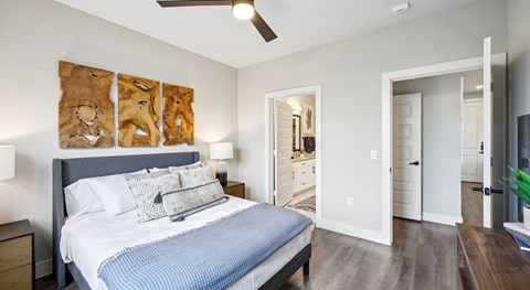 A bedroom with a bed, nightstand, and artwork on the wall.