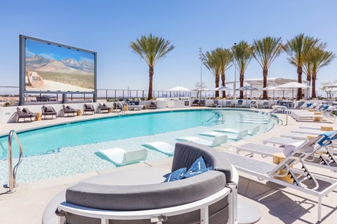 A large screen is mounted on a wall above a pool.