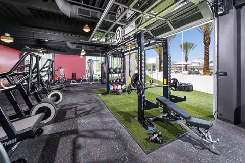 A gym with a red wall and black flooring.
