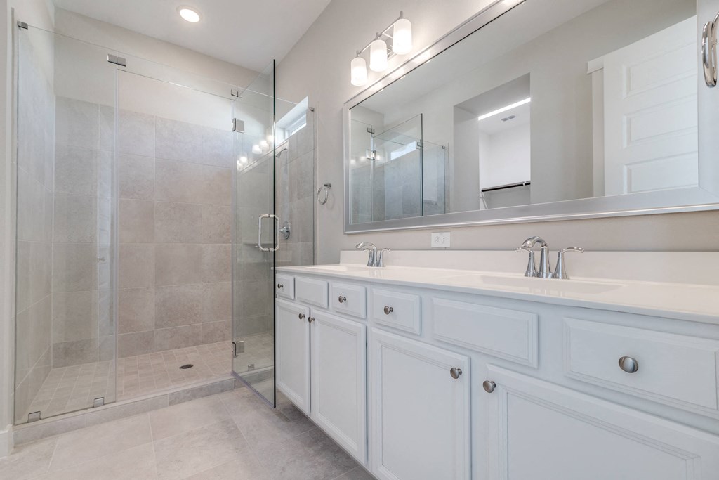 a bathroom with white cabinets and a shower and a sink