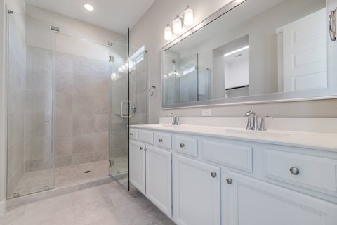 A	Luxury Two-Bedroom Homes for Rent in Houston, TX - East Heights - Bathroom with Double Vanity Sink, Shower, White Cabinets, and Mirror.
