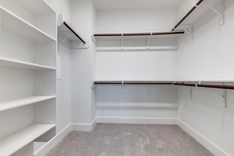 an empty walk in closet with white walls and shelves