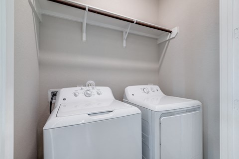 a washer and dryer in a laundry room with a shelf over the top