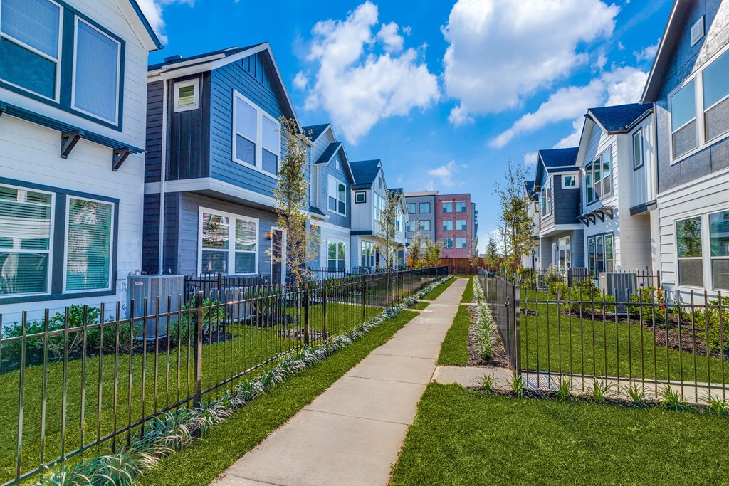 a row of homes with a sidewalk and green grass