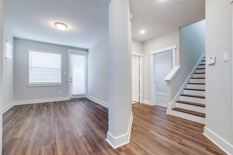 an empty living room with wood flooring and a staircase