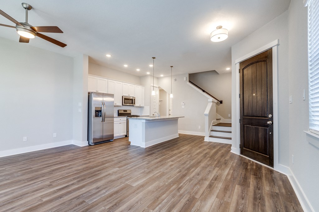 a living room with a kitchen and a ceiling fan
