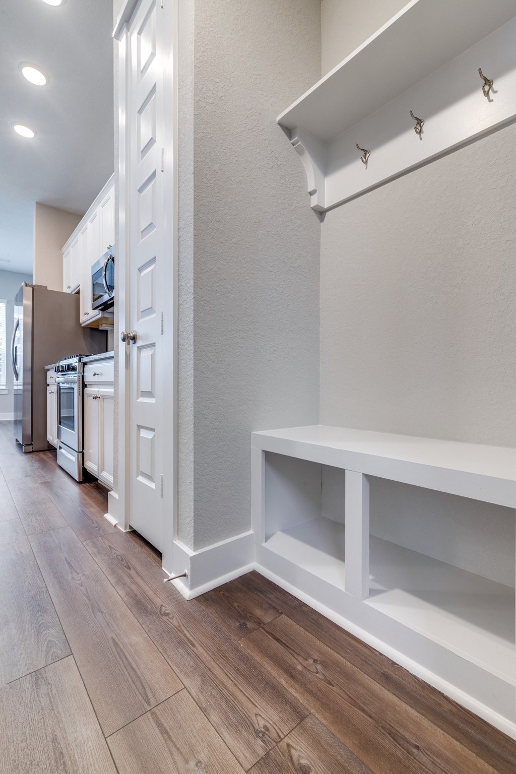 a renovated kitchen with white cabinets and white appliances and a wood floor