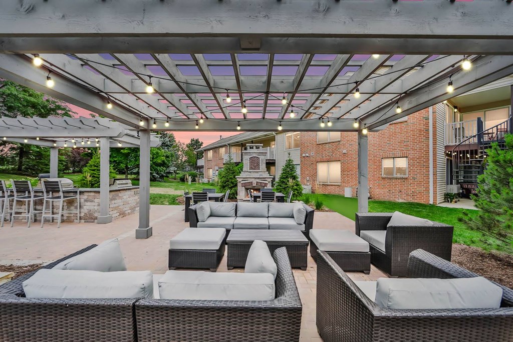 a covered patio with couches and tables under a pergola