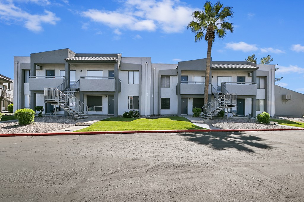 Dog-Friendly Apartments in Glendale, AZ - Ardella n 67th - Building Exterior with Paved Entrance, Manicured Lawn, and Parking Lot.