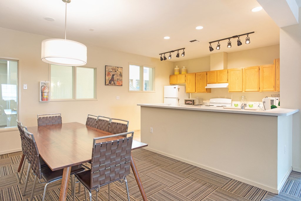 Apartments in Puyallup WA for Rent - One Canyon Place - Kitchen with 8-Seater Dining Set, Track-Lighted Wide Counter, White Appliances, and Wooden Hanging Cabinets
