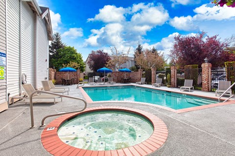 Apartments for Rent in Puyallup WA - One Canyon Place - Fenced-In Sparkling Pool with Whirlpool Spa, Lounge Seating, Umbrellas, Tables, and Chairs