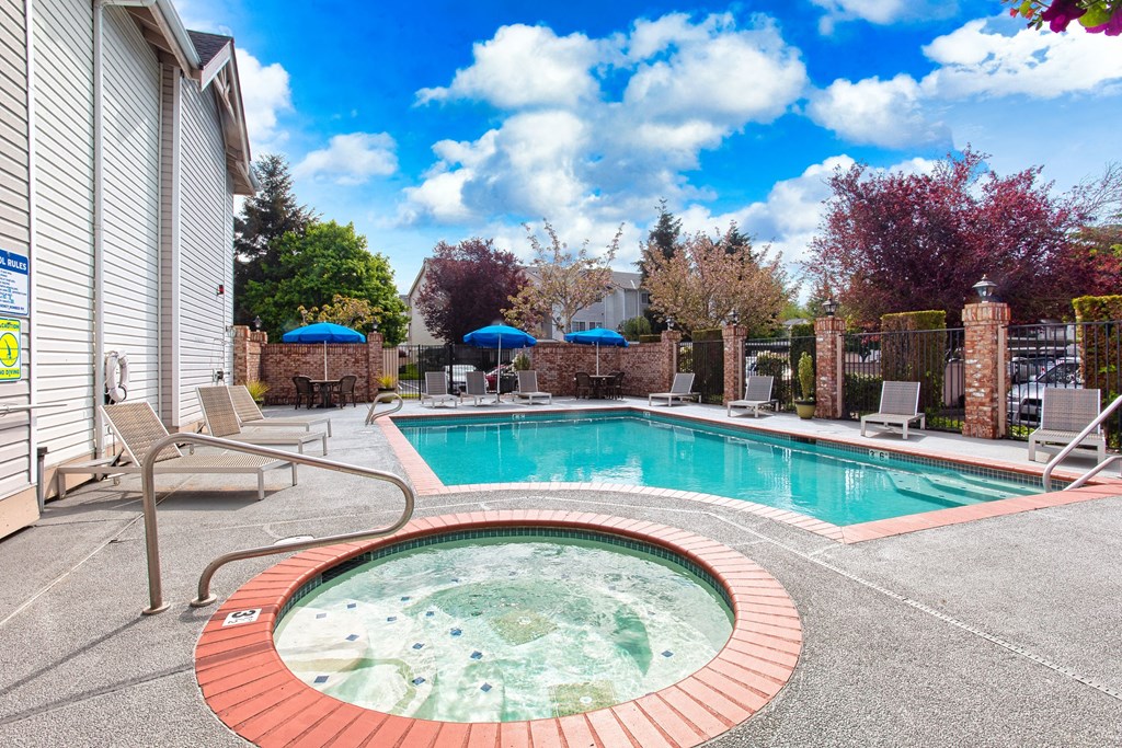Apartments for Rent in Puyallup WA - One Canyon Place - Fenced-In Sparkling Pool with Whirlpool Spa, Lounge Seating, Umbrellas, Tables, and Chairs