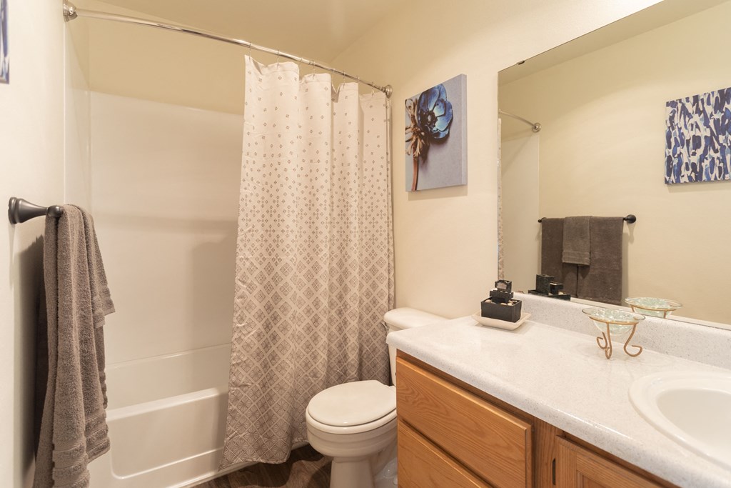 Two-Bedroom Apartments in Puyallup, WA - One Canyon Place - Bathroom with a Large Mirror, Bathtub, and Wood-Style Flooring.