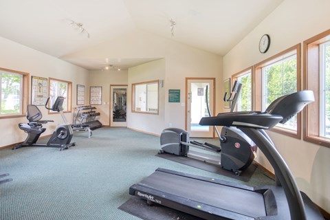 Garden-Style Apartments in University Place, WA, with In-Unit Washer and Dryer - Carriage House - Fitness Center With Treadmills, Stationary Bike, Weight Bench, Dumbbells, and Large Windows.