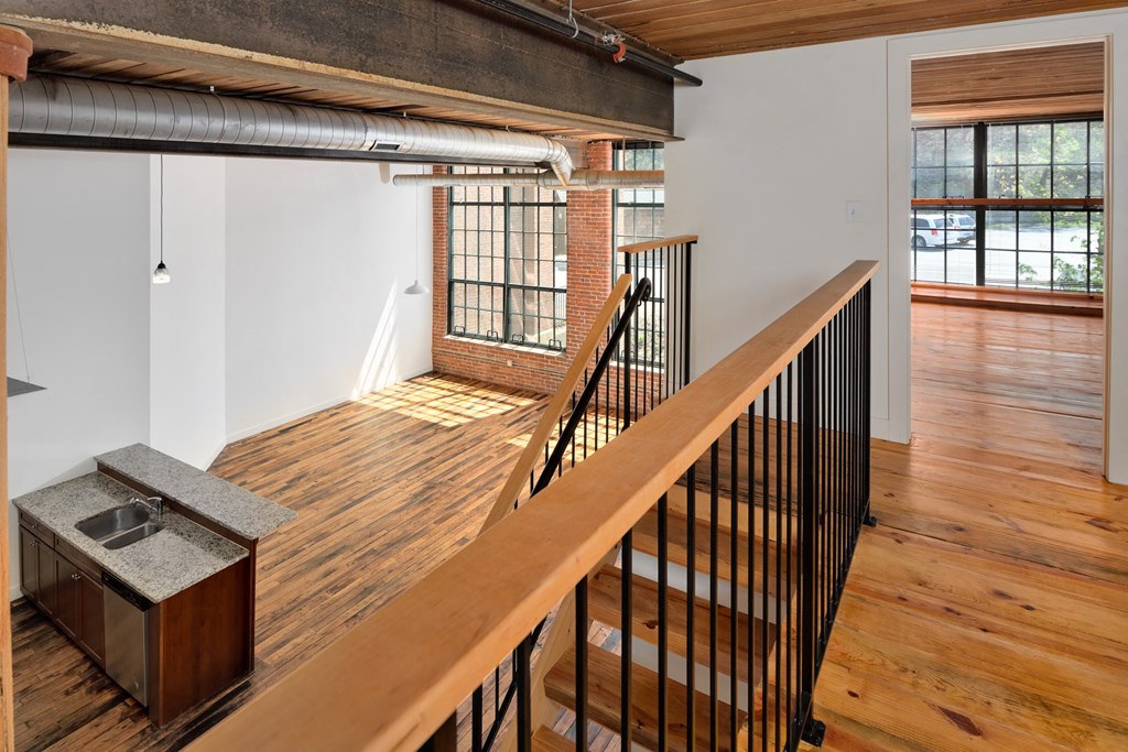 Modern loft apartment interior with exposed brick, wood ceiling, and large windows.
