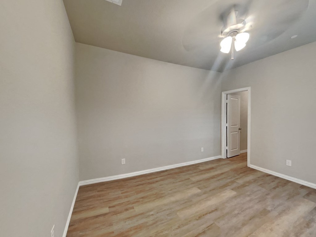 an empty living room with wood flooring and a ceiling fan