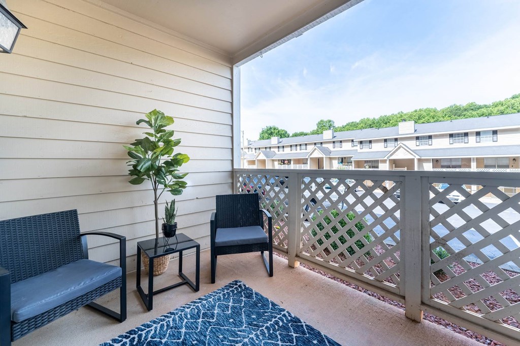 a balcony with two chairs and a potted plant