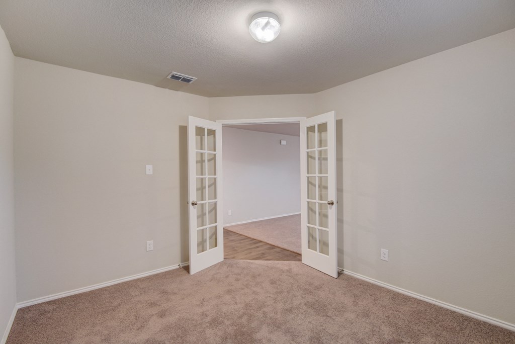 an empty living room with white doors and carpet