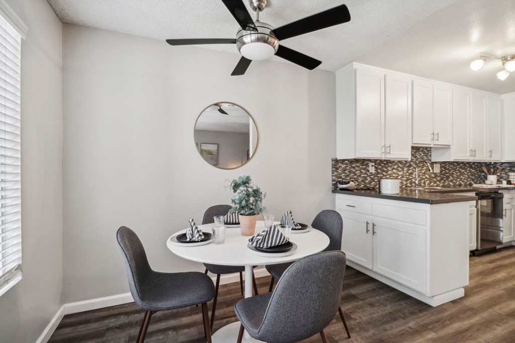 A dining room with a table, chairs, and a ceiling fan.