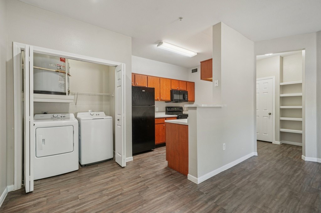 A kitchen with a black refrigerator, white oven, and white dishwasher.