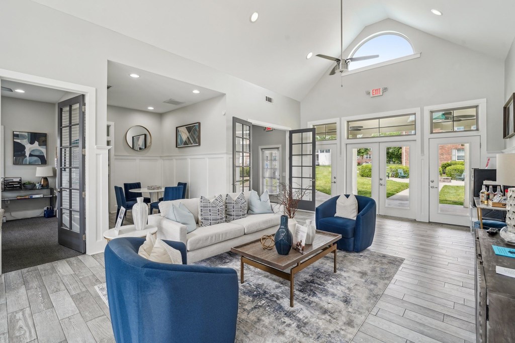Bright and airy clubhouse lounge area with white sofa, blue armchairs, and dining space.