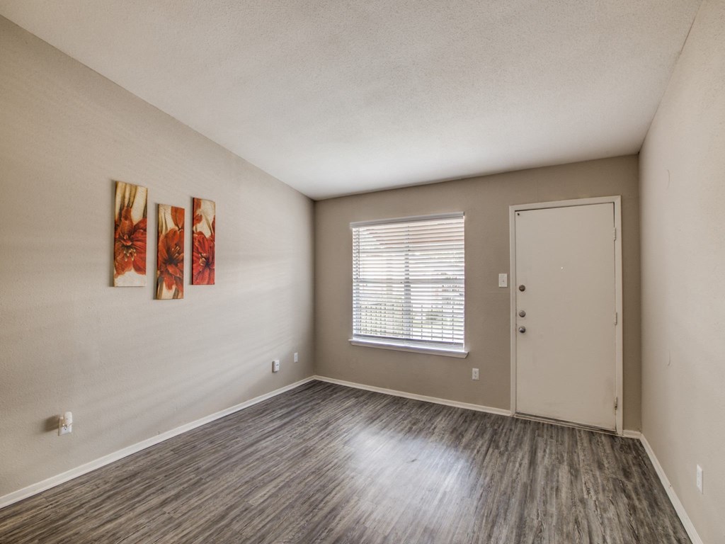 an empty living room with wood flooring and a white door