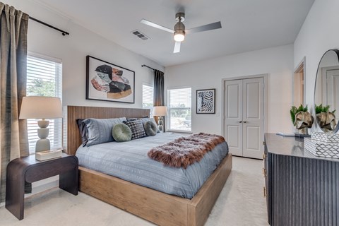 A bedroom with a large bed and a ceiling fan.