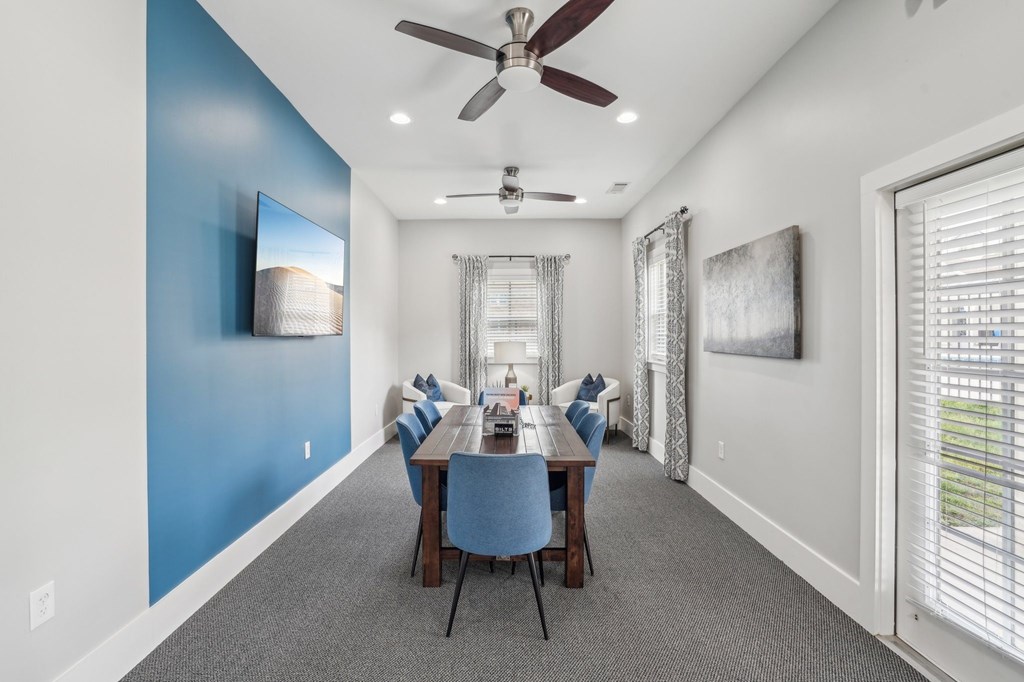Modern dining room with blue chairs, wood table, and blue accent wall.
