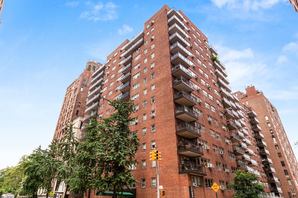 a red brick building with balconies and trees in front of it