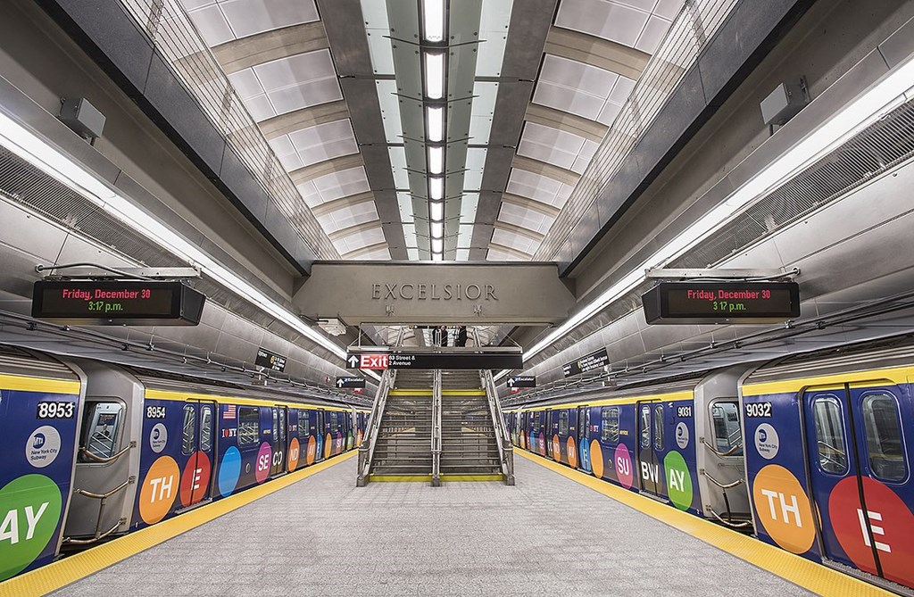 a subway station with a subway train on the platform and a staircase