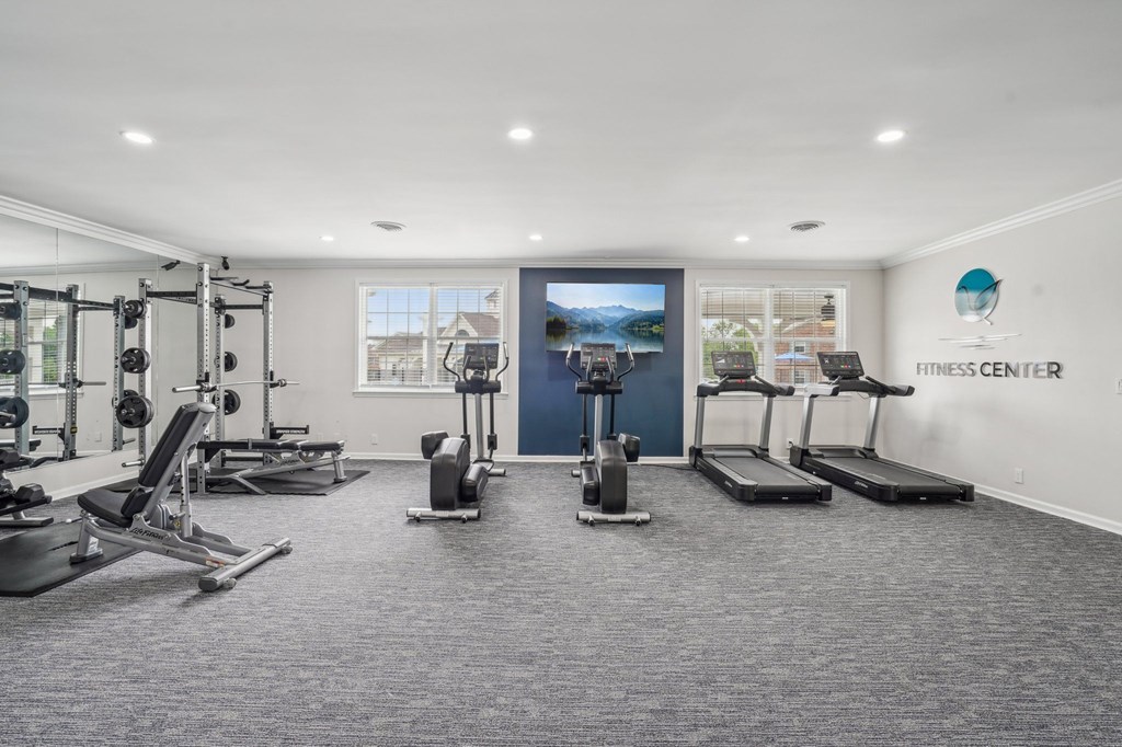 Bright fitness center with treadmills, elliptical machines, and weightlifting equipment.