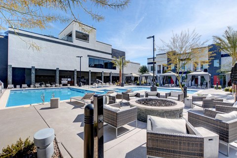 Summerlin, NV, Luxury Apartments Near Town Square Las Vegas - EVO Apartments - Swimming Pool With Lounge Seating, Private Cabanas, Fire Pit Area, Palm Trees, And Modern Apartment Buildings.