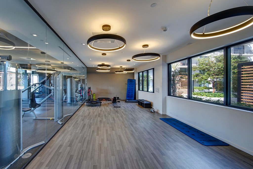a fitness room with yoga mats and mirrors in a building with large windows