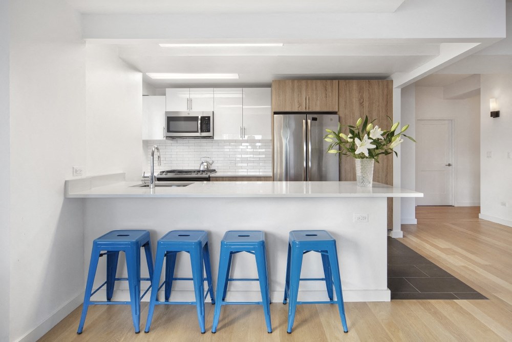 a kitchen with three blue stools in front of a counter top