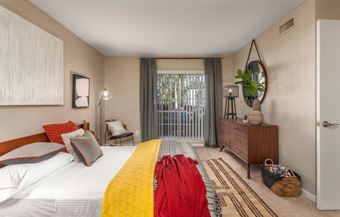 A bedroom with a large bed and a window with curtains.
