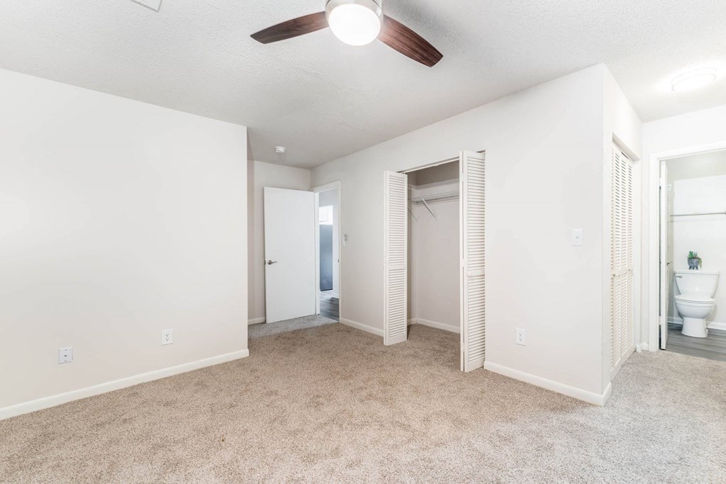 an empty living room with a ceiling fan and a bathroom
